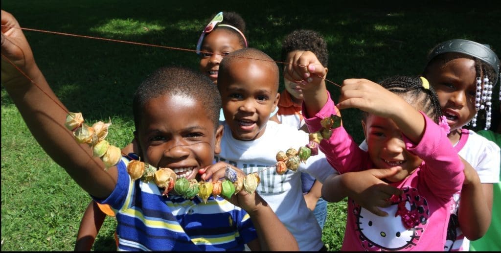 Small children smiling & holding up their crafts